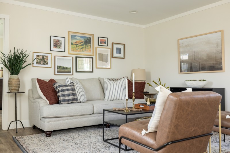 Living room of a Tempo manufactured home with neural couch, leather chairs, coffee table and gallery wall.