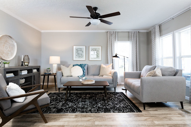 Living room of a CrossMod™ home with gray couches and chair and a black rug.