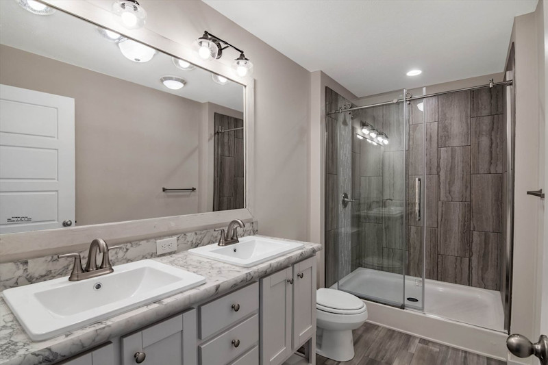 A contemporary style bathroom with a walk in shower and double sink vanity.