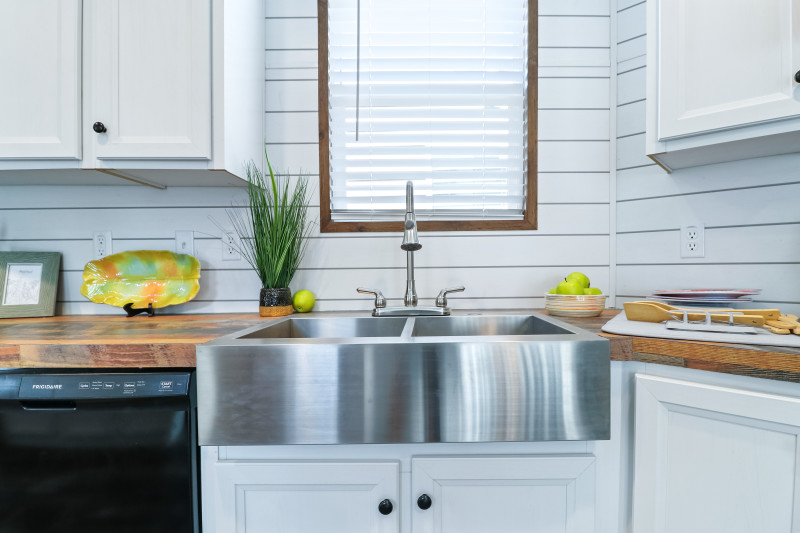 Metal apron front farmhouse sink in a Clayton Built home with shiplap covered walls.