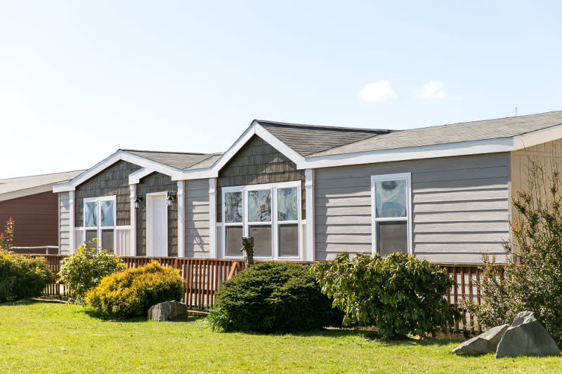 Exterior of a tan manufactured home with a white front door and white trim.