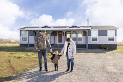  Danica, Jesse and their young daughter Soryah standing in front of their manufactured home.