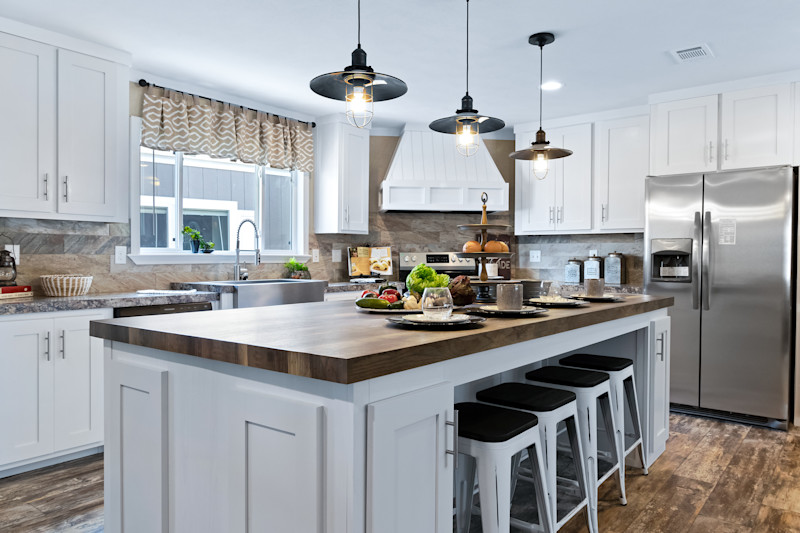 Modular home kitchen with a large breakfast bar and white cabinets.