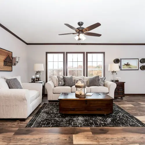 The Avalyn living room fills with natural light from large windows accented with exposed wood frames.