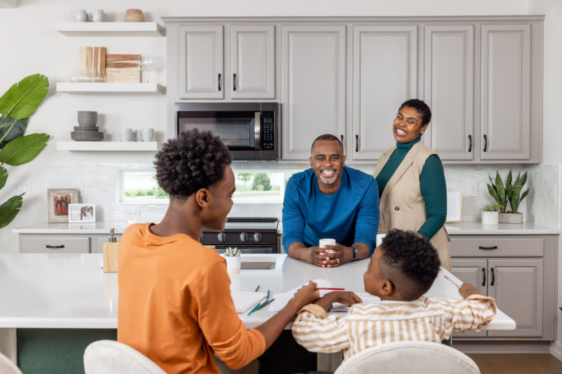 Family spending time together and laughing around the kitchen island in their manufactured home.