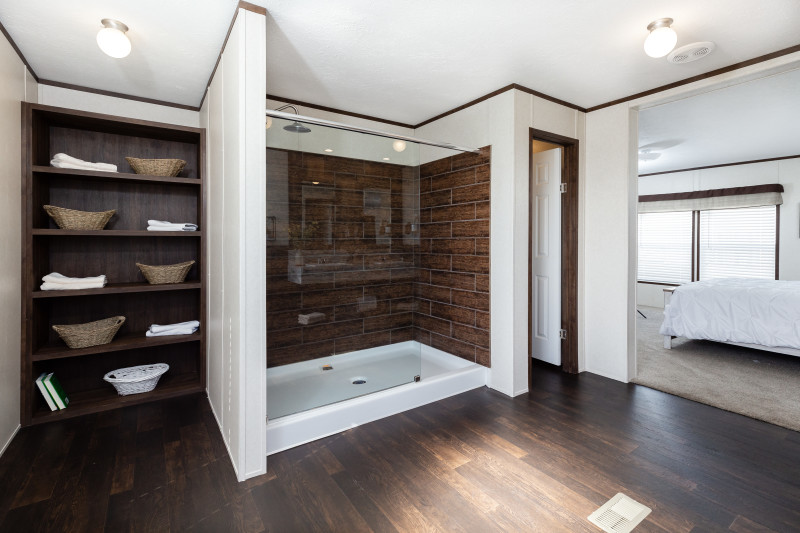 Manufactured home bathroom with glass front shower, wooden floors and built-in shelving