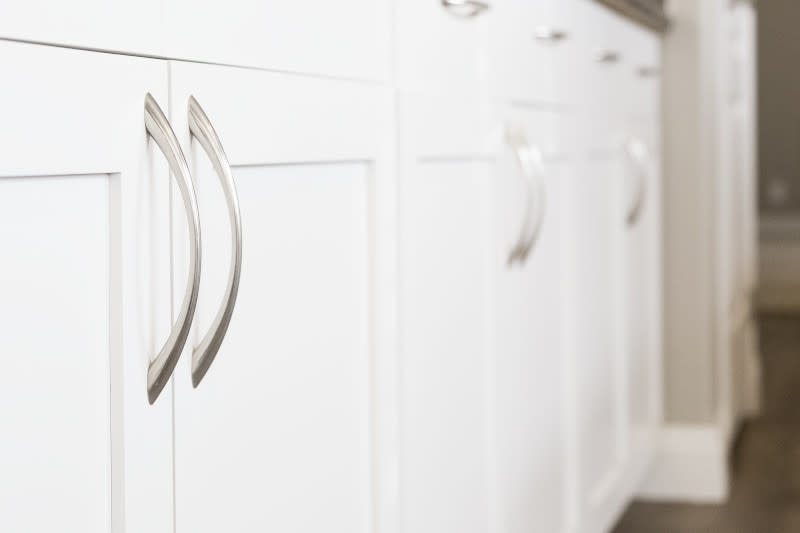 Close up of white kitchen cabinets with silver handles.