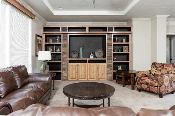 The [model name] features this living room with a built-in entertainment center and book shelves, along with a tray ceiling, crown molding and triple windows.