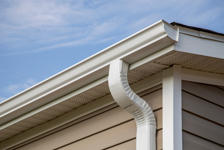Close up of white manufactured home gutters and tan siding.