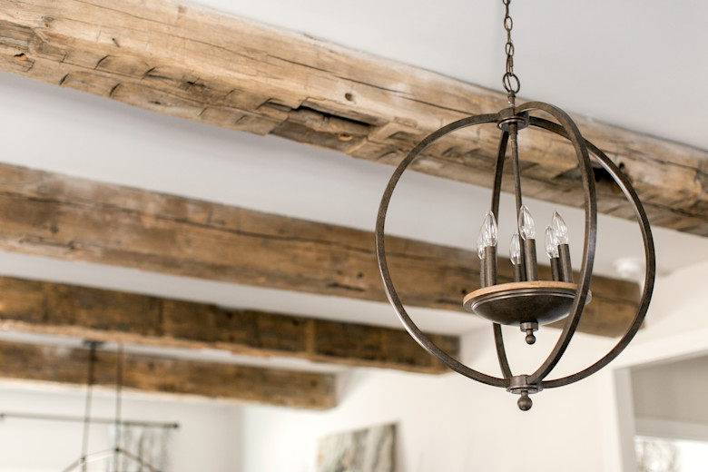 Manufactured home living room with rustic ceiling beams and copper cylindrical chandelier.