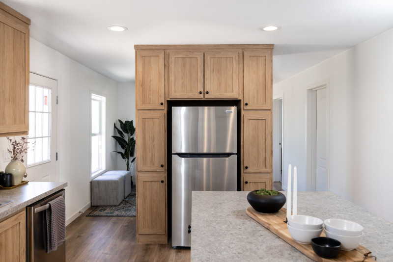 Kitchen of a Clayton manufactured home with light wood cabinet wall around the fridge, white walls and gray countertops