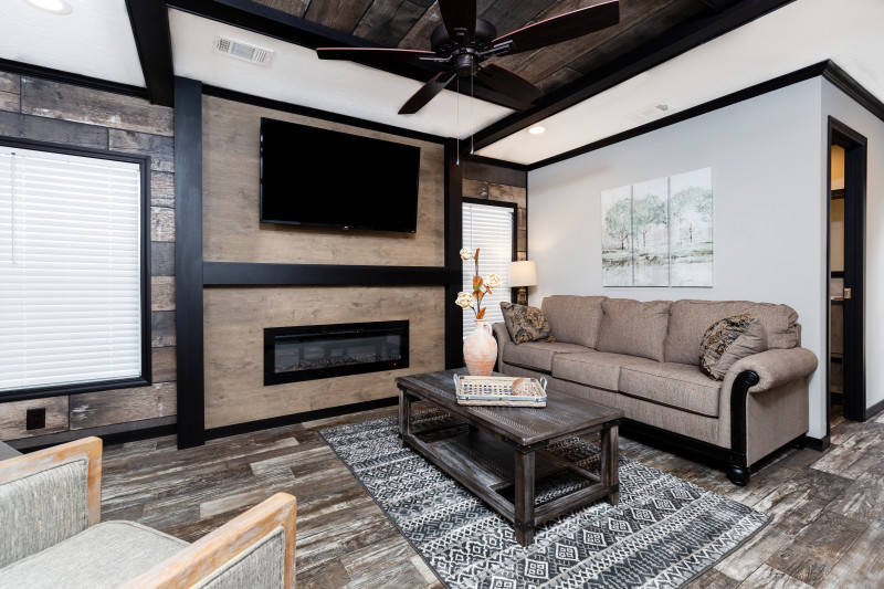 Den with shiplap walls, fireplace, light walls and wood floors in a manufactured Clayton home.