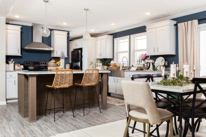 Kitchen and dining room of the Ripley (25BLD28583AH) with blue walls, white cabinets and boho décor.