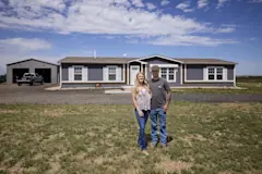 Abbi and Perry Thompson standing in front of their home and shop