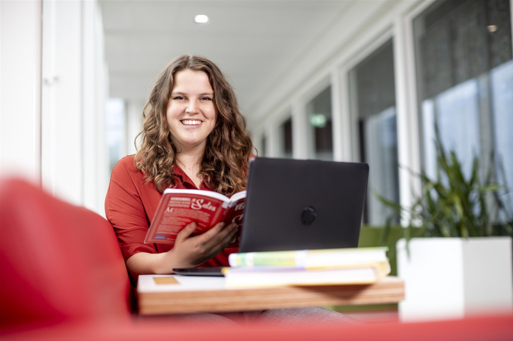 Student met boek en laptop. 