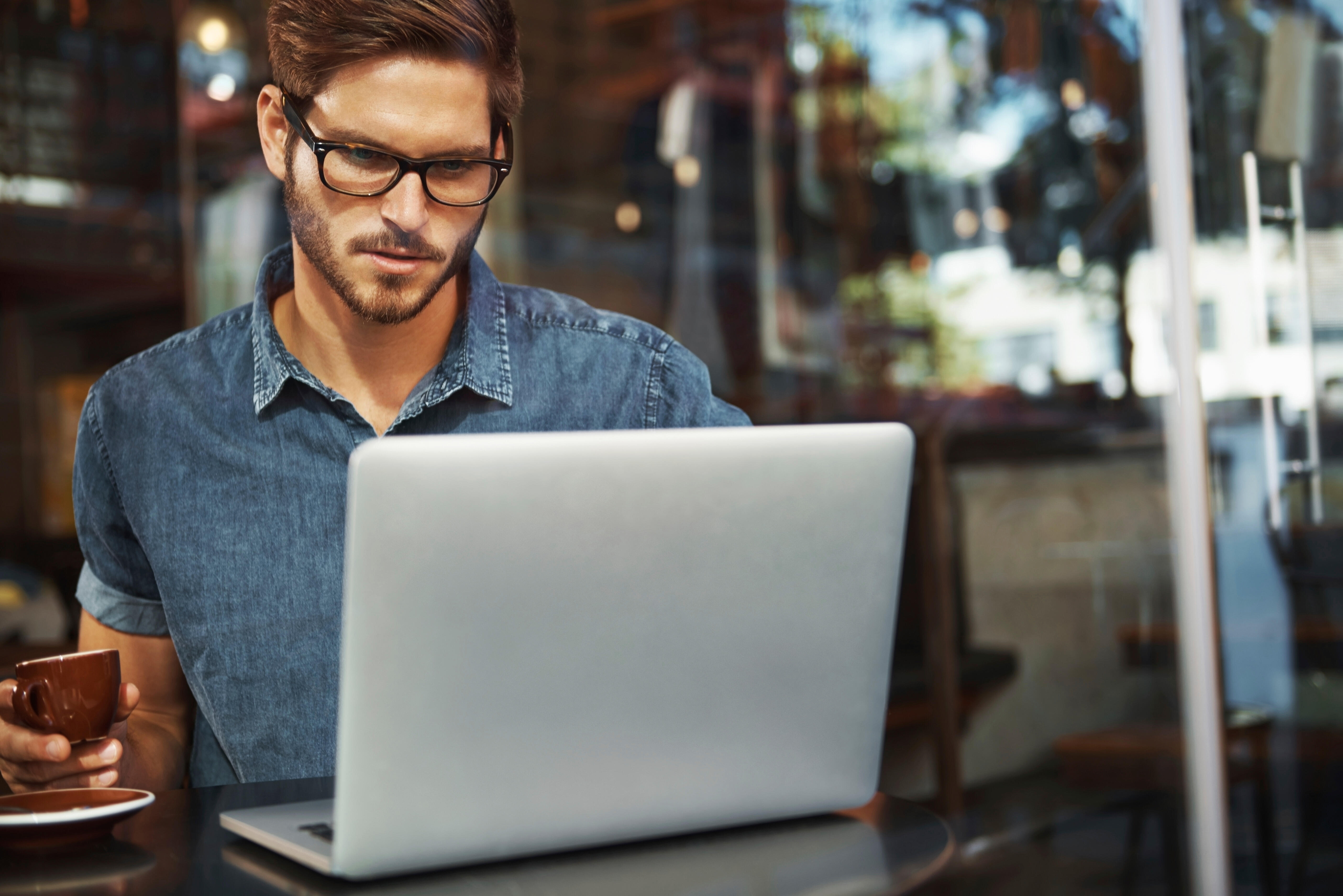 Stockfoto Junger Mann im Bistro am Laptop