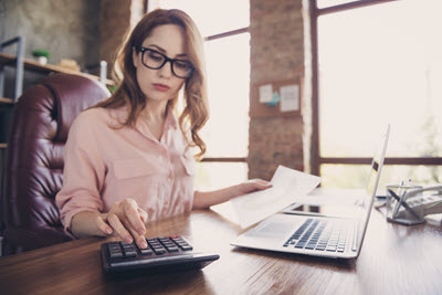 Stockfoto: Frau am Tisch mit Laptop und Tischrechner