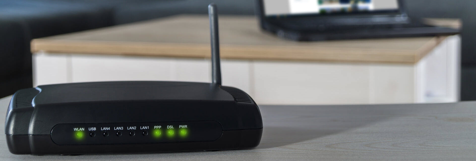 Ein WLAN-Router mit Laptop im Hintergrund