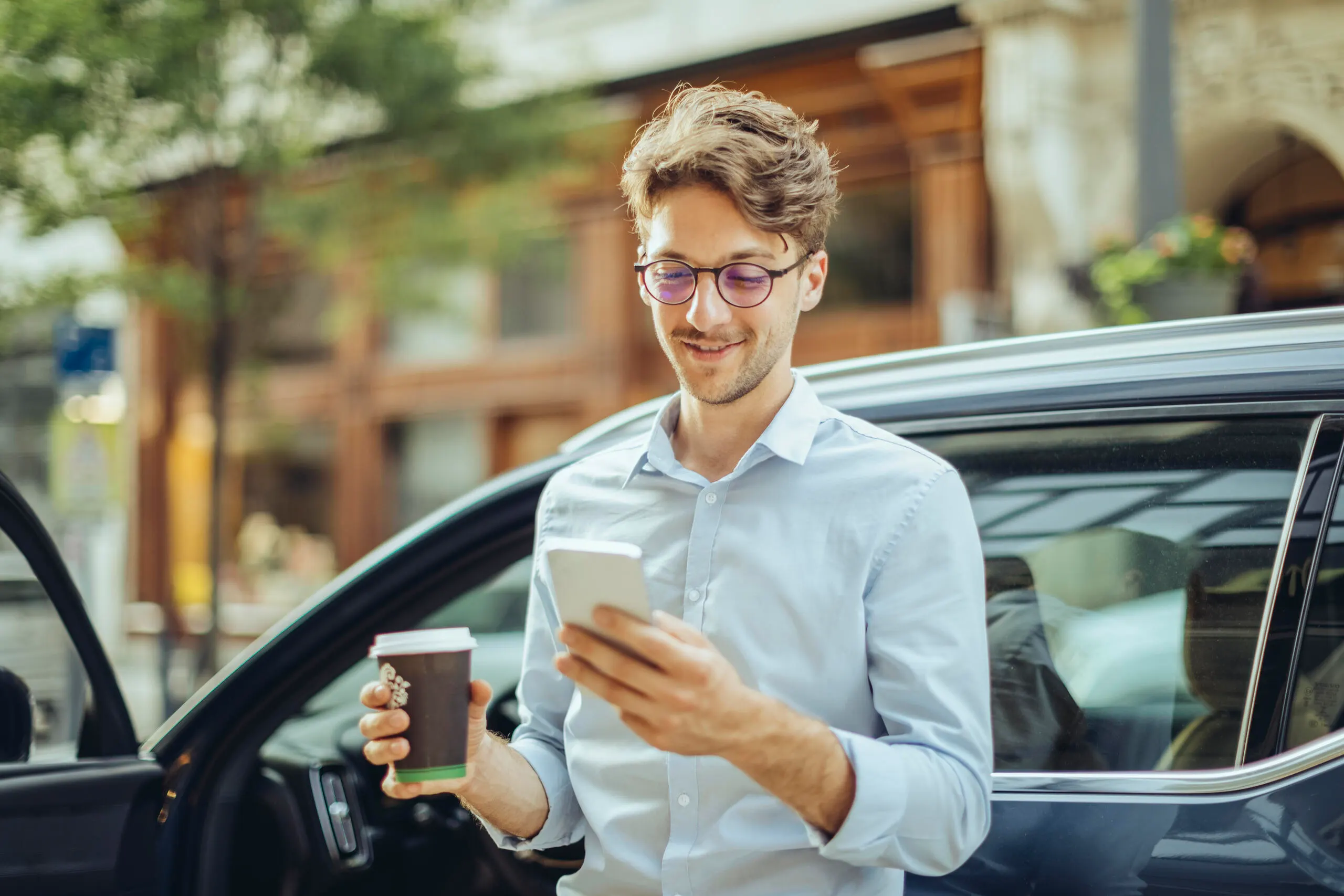 Stockfoto Junger Mann mit Handy und Kaffeebecher
