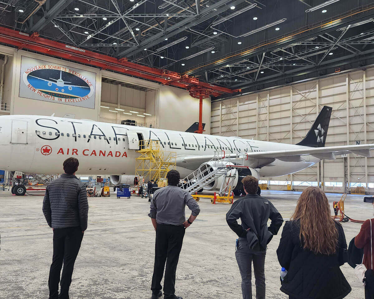 Aviation students view a large airplane inside a hangar