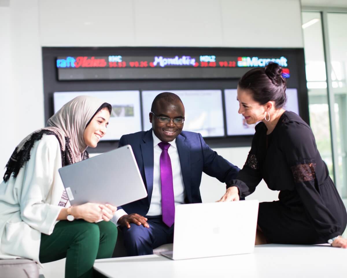 Three colleagues with laptops sitting and talking