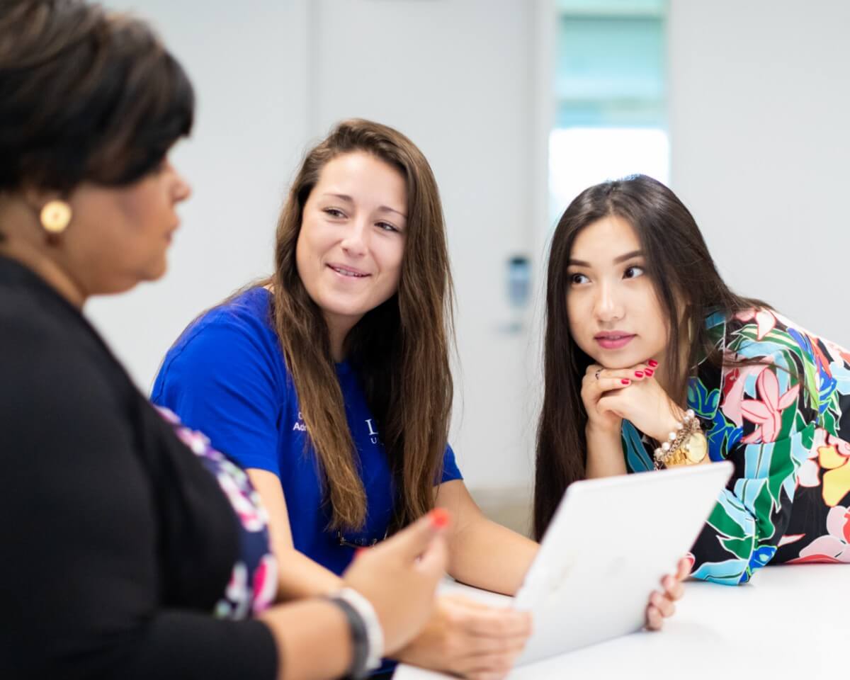 Two Lynn marketing students in classroom, focusing attention on their instructor