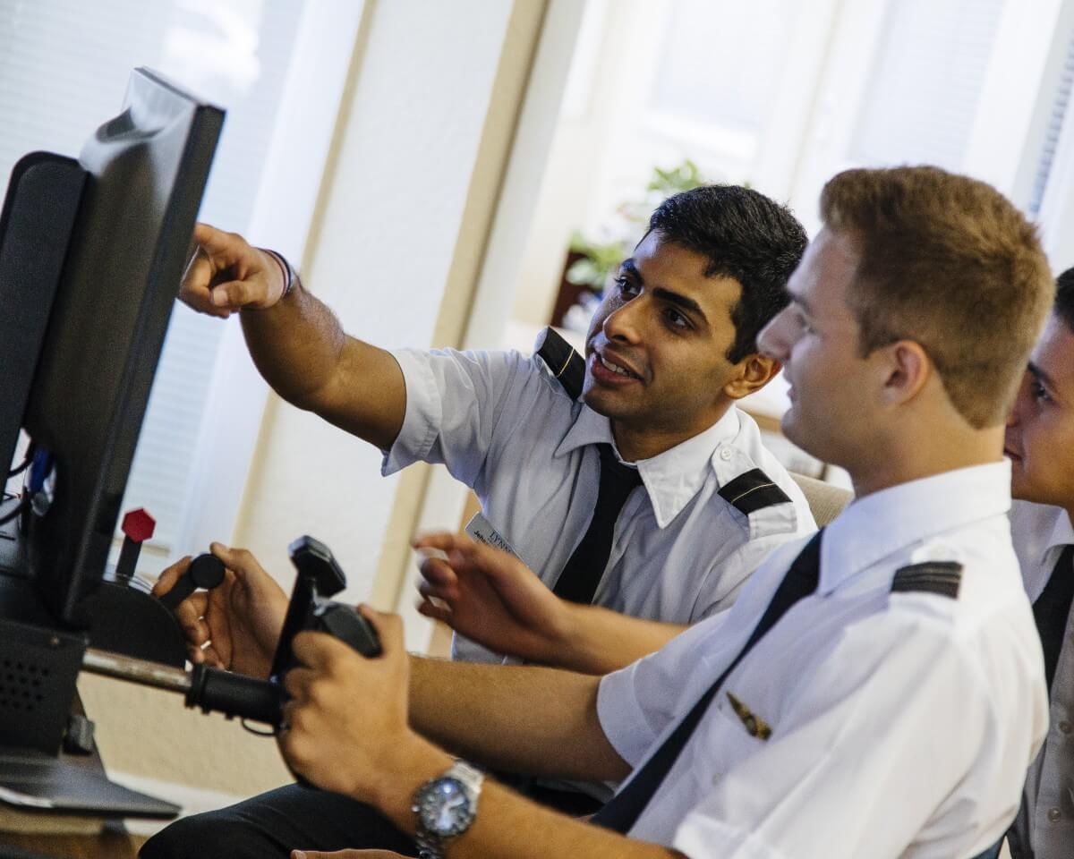 Two Lynn aviation students in uniform looking at a computer