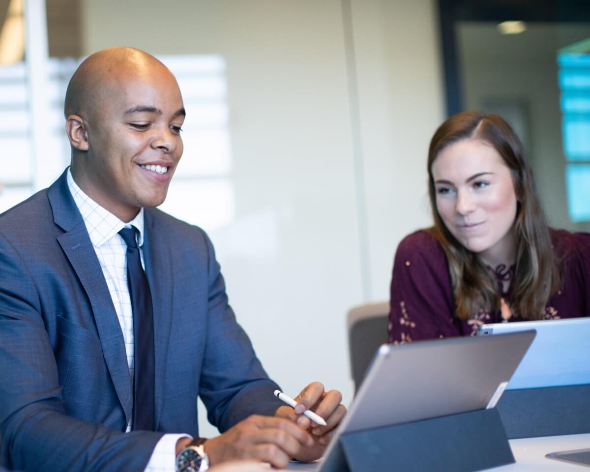 Two colleagues sitting and working on laptops in a modern conference room