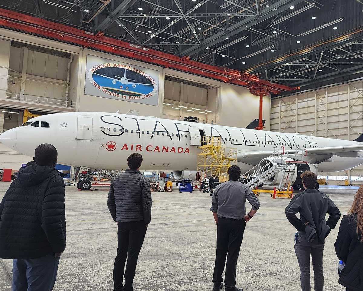 Several people standing in an airplane hangar, viewing a jet airplane