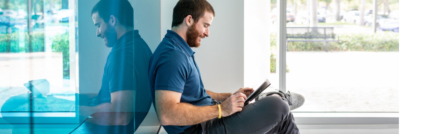 Lynn student working on a tablet while sitting outside a building