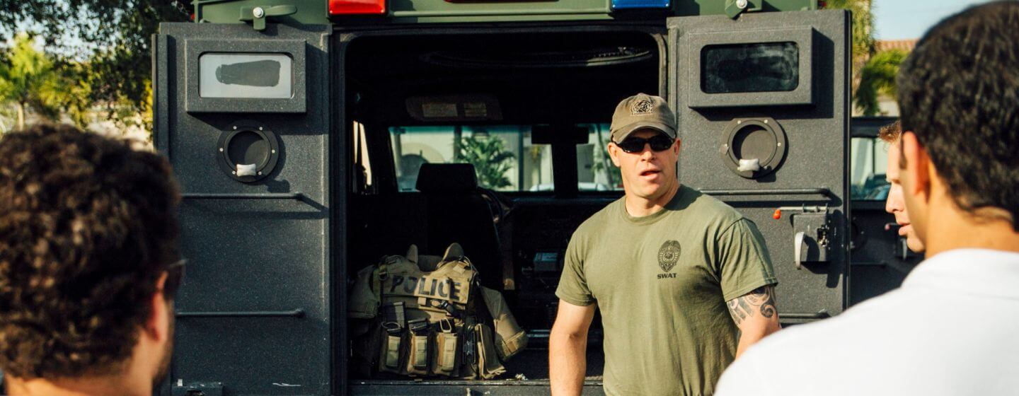 Group of men standing outside a truck with tactical gear