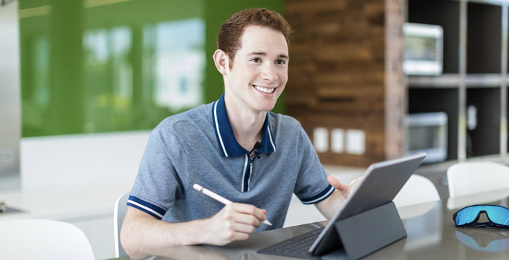 A smiling student learning with a tablet.