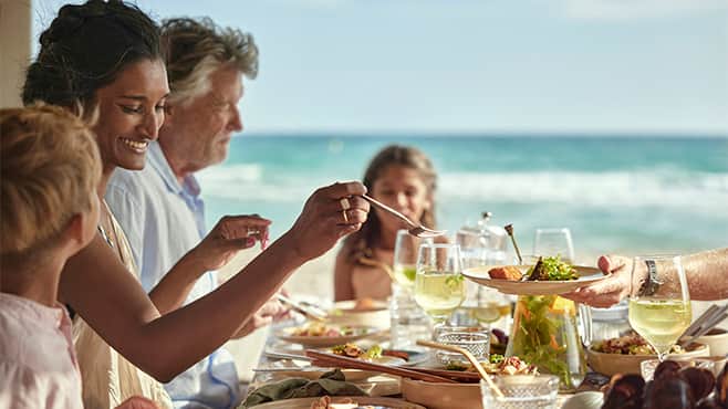 Perhe nauttii lounasta meren äärellä TUIn äkkilähdöllä.