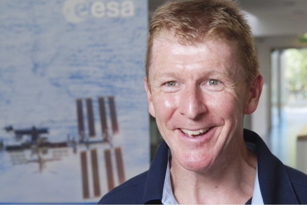 Tim in a blue shirt standing in front of an international space station