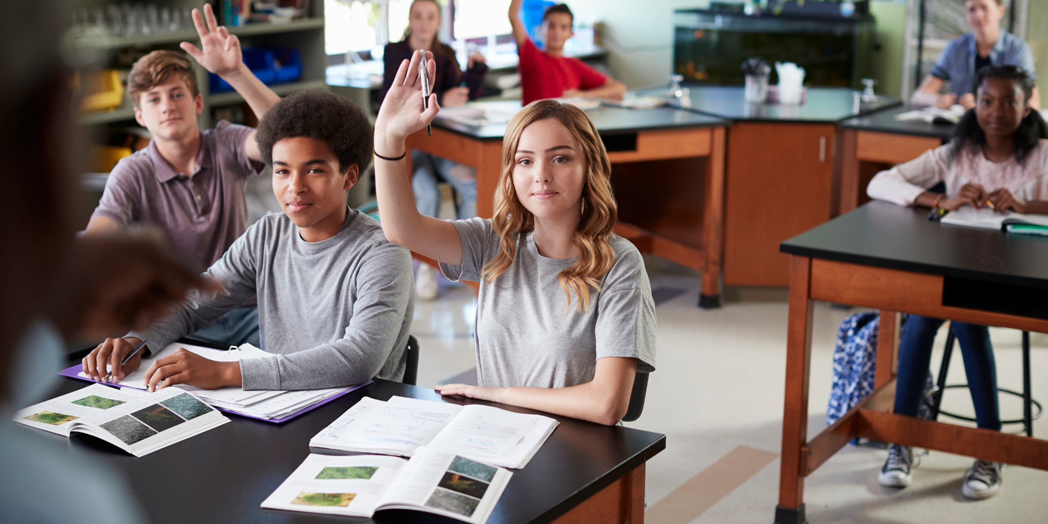 Female student in biology class raising hand to answer question