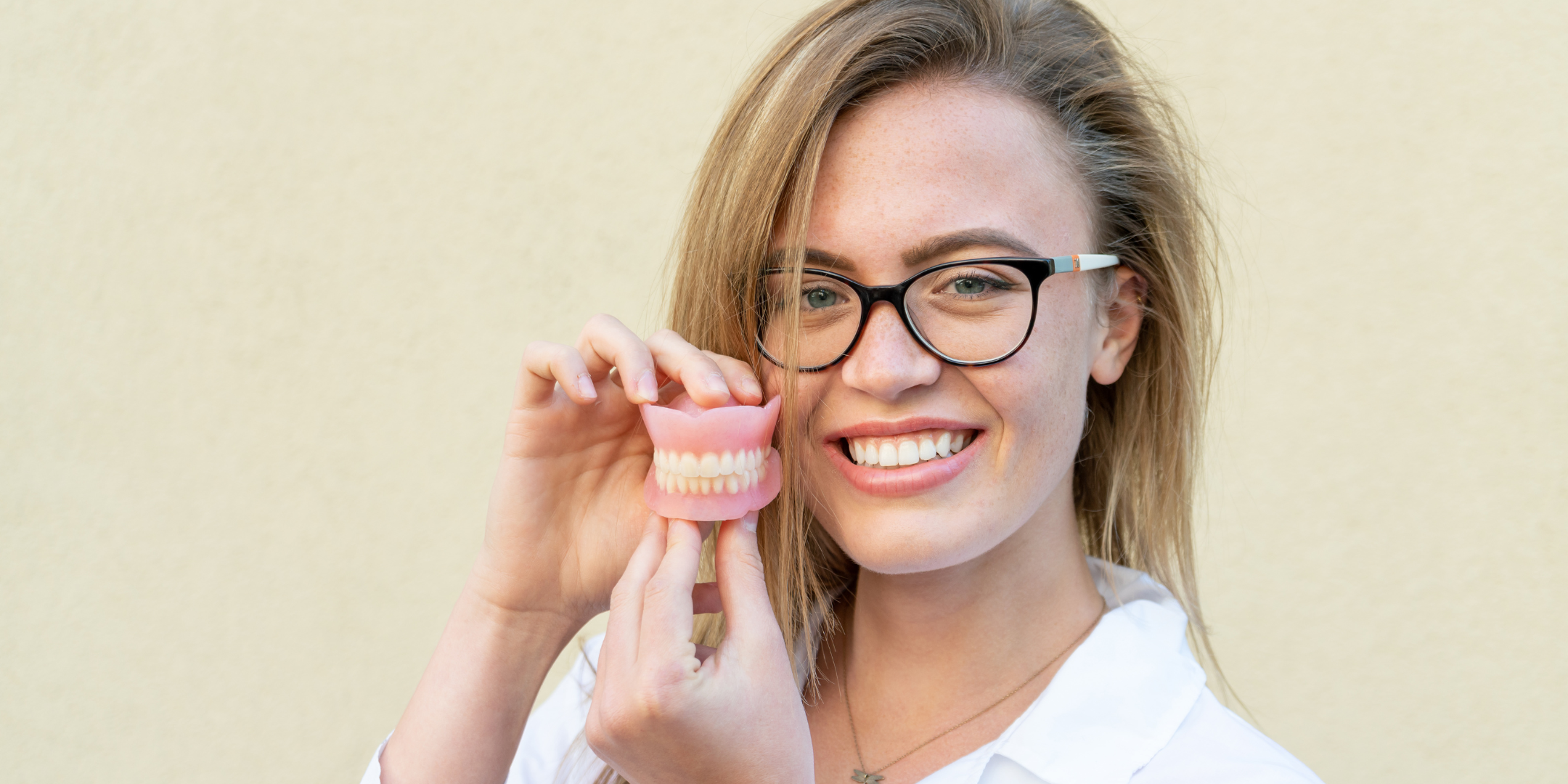 Dentist holds dentures in her hands, smiling
