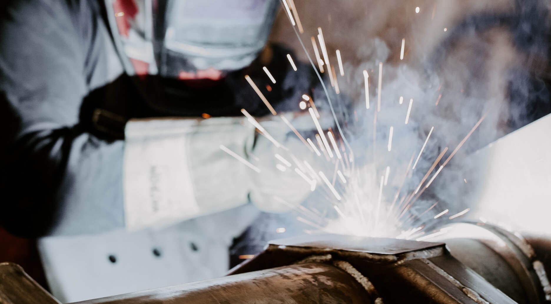 a professional welder working with a metal pipe