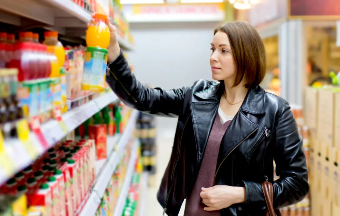 A woman is choosing a drink in a supermarket.