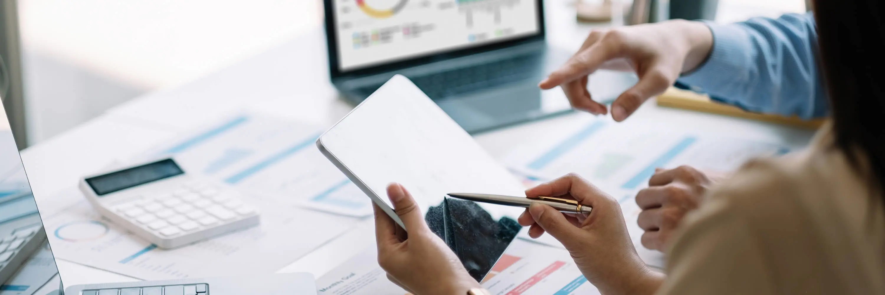 Two people working on a spreadsheet at a desk.