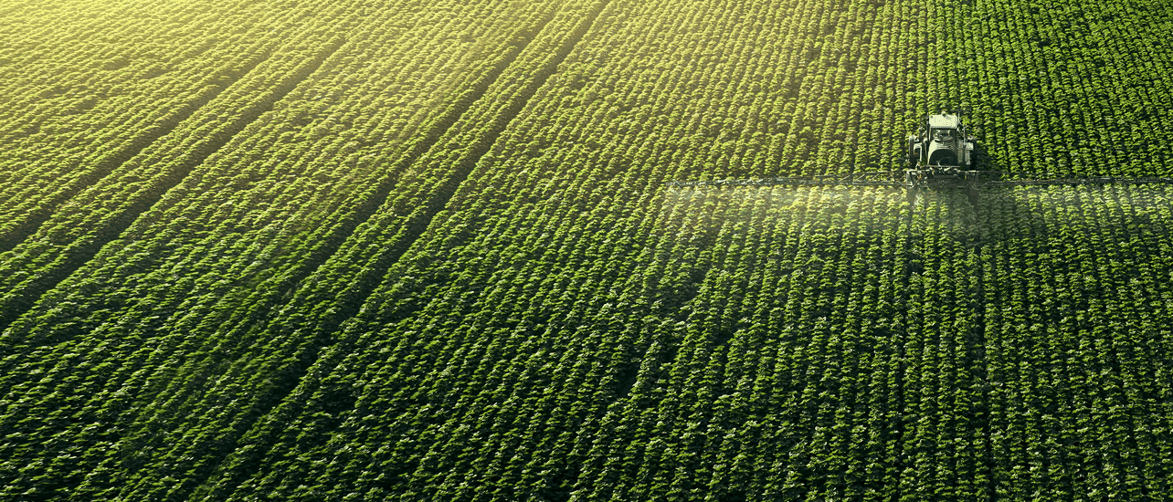 A tractor sprays a field, prominently featuring a purple label indicating its use in a label database.
