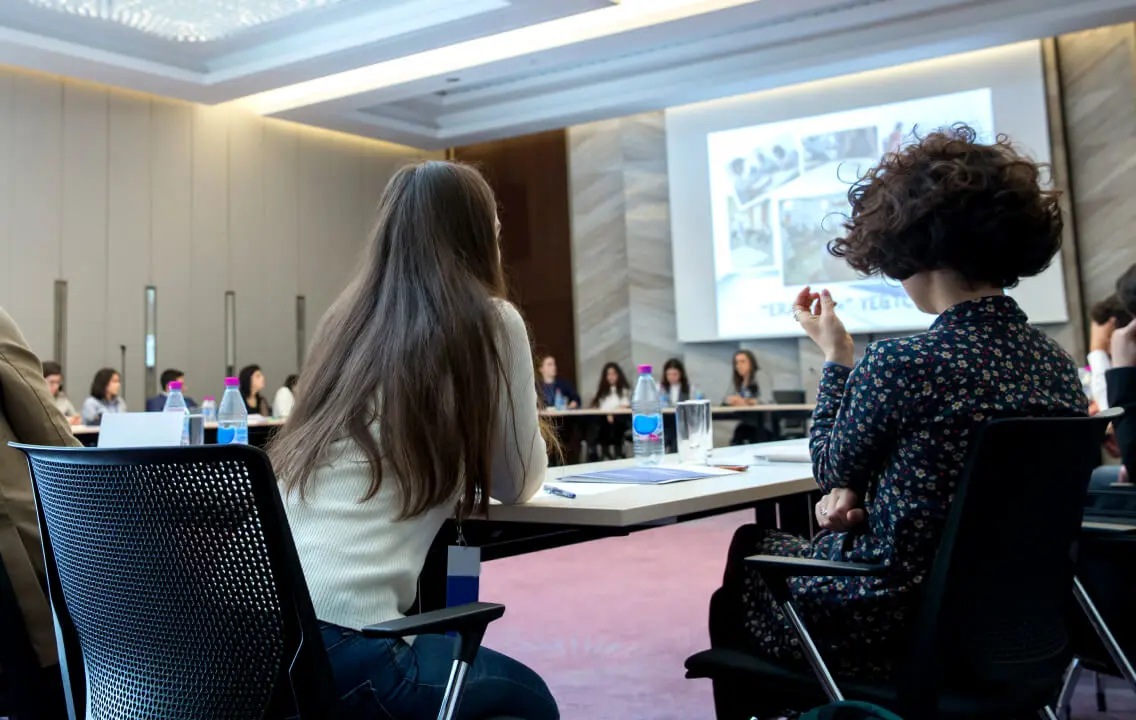 A group of people sitting at a table in a conference room.