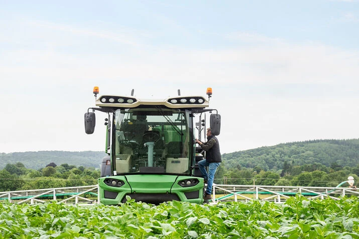 A man operates a tractor in a field, utilising farm management software for efficient agricultural practices.
