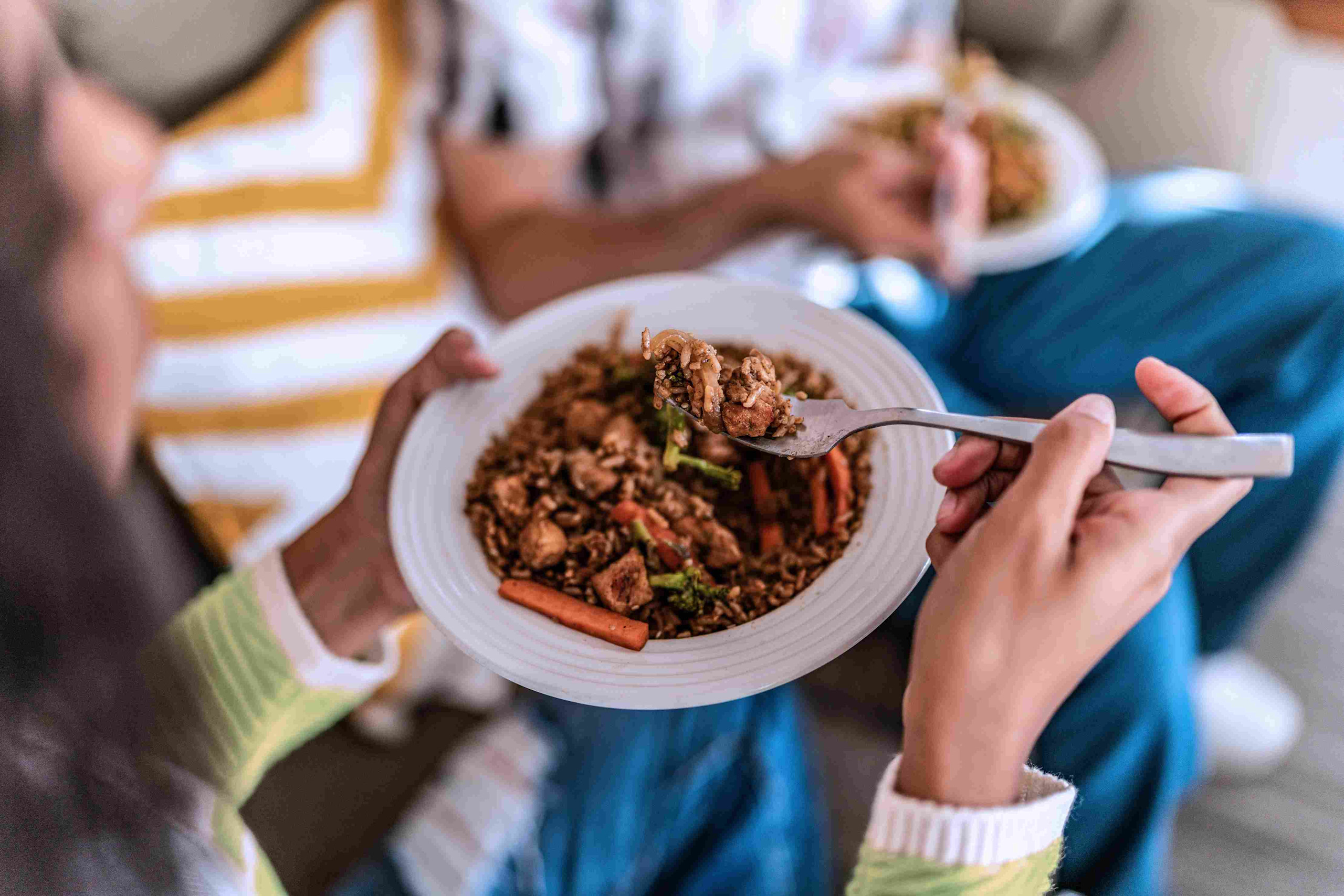 Woman eating InnovAsian chicken fried rice. 
