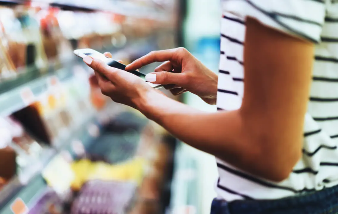 A person using a cell phone in a grocery store.