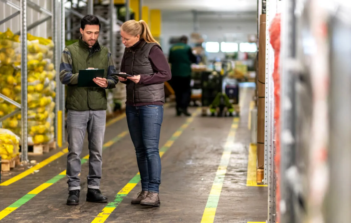 Two people looking at a tablet in a warehouse.