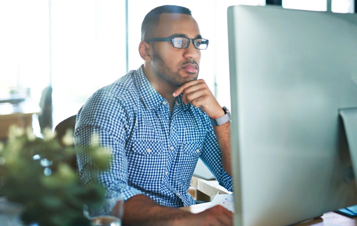 A man sitting in front of a computer screen.