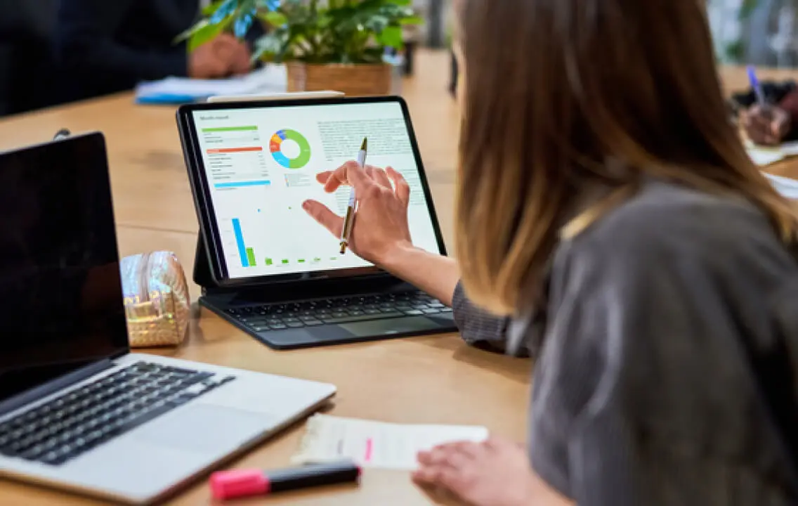 A woman is looking at a graph on a laptop.