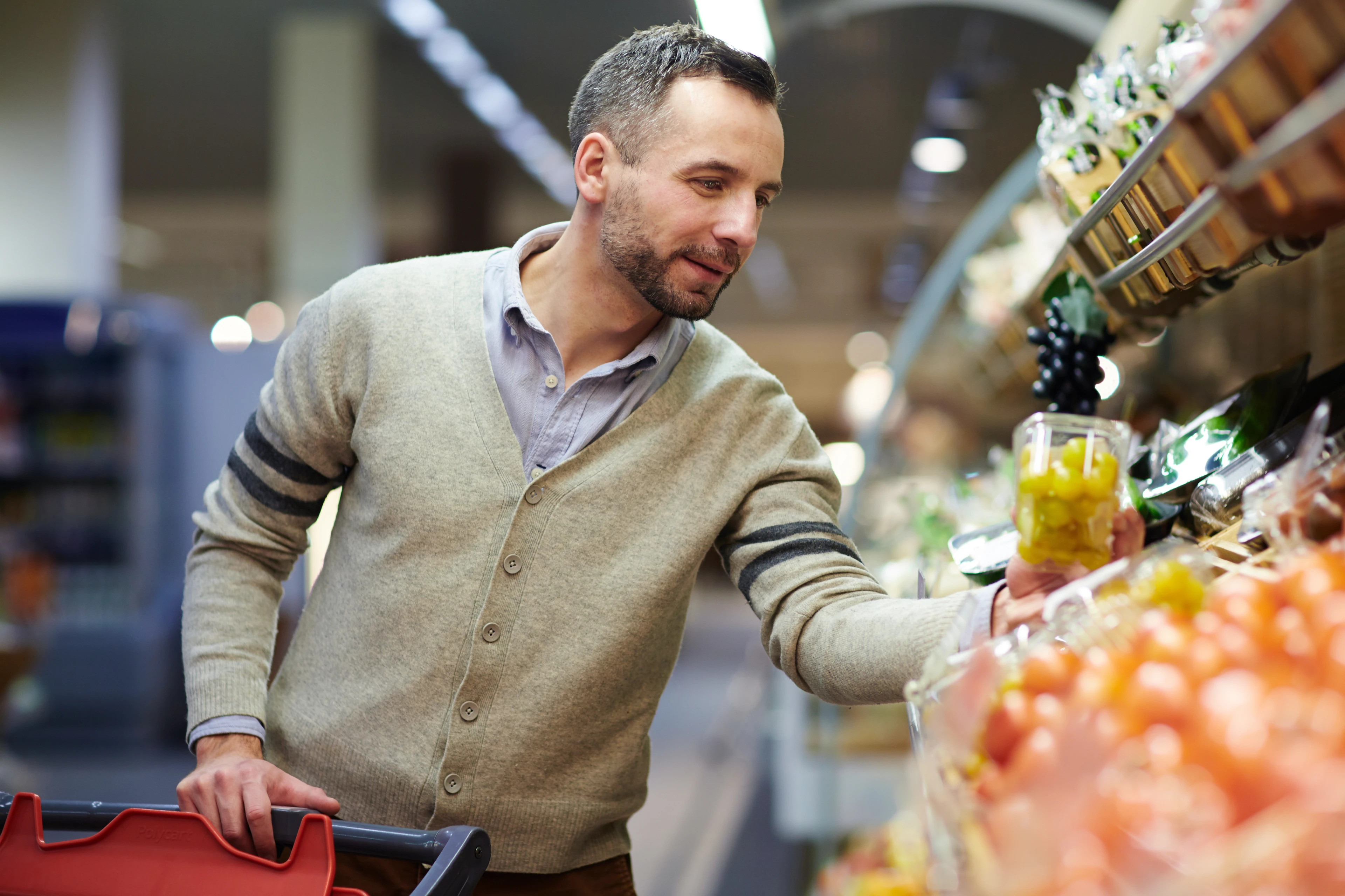 Homme examinant des raisins à l’épicerie en fonction d’une stratégie promotionnelle.