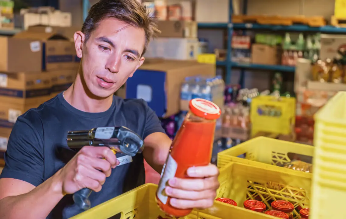 A man is scanning a bottle in a warehouse