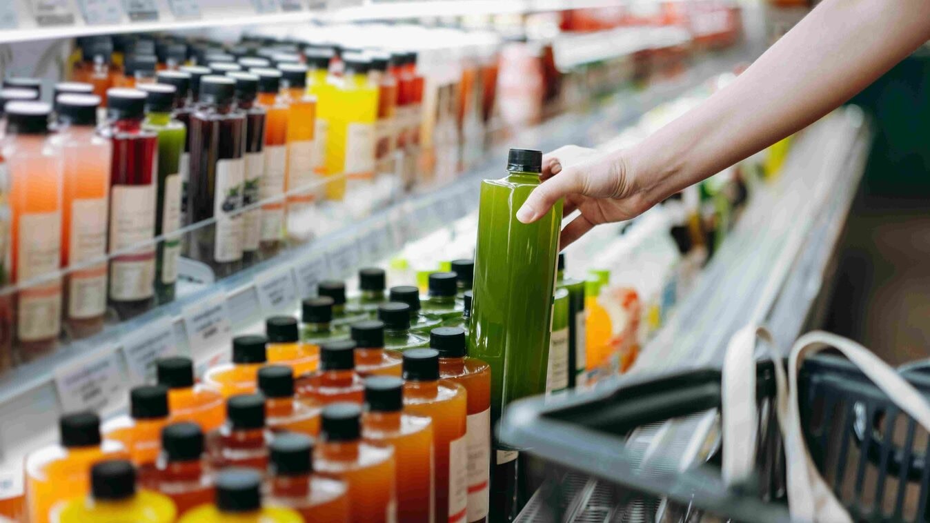 Hand grabbing juice out of grocery store cooler